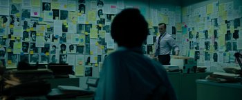 Movie still from “The Report” (2019), directed by Scott Z. Burns – A man standing in front of a wall covered with papers; Medium shot, Over the shoulder angle