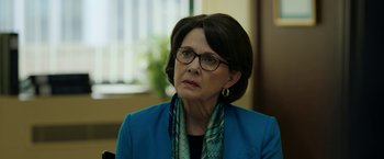 Movie still from “The Report” (2019), directed by Scott Z. Burns – An older woman wearing glasses and a blue jacket; Close Up shot, Over the shoulder angle