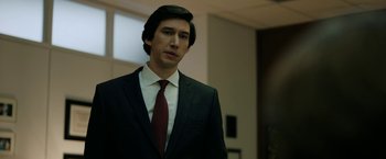 Movie still from “The Report” (2019), directed by Scott Z. Burns – A man wearing a suit and tie standing in a room; Close Up shot, Low angle