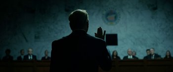Movie still from “The Report” (2019), directed by Scott Z. Burns – A man in a suit is taking his oath in front of a judge; Medium shot, Low angle