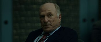 Movie still from “The Report” (2019), directed by Scott Z. Burns – An older man wearing a suit and tie; Close Up shot, Low angle