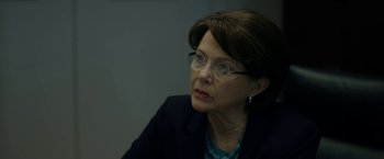Movie still from “The Report” (2019), directed by Scott Z. Burns – An older woman wearing glasses and a jacket; Close Up shot, Over the shoulder angle