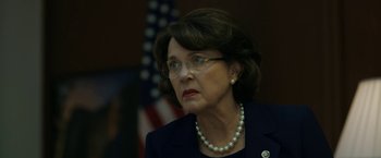 Movie still from “The Report” (2019), directed by Scott Z. Burns – An older woman wearing glasses and a pearl necklace; Close Up shot, High angle
