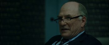 Movie still from “The Report” (2019), directed by Scott Z. Burns – An older man wearing glasses and a suit; Close Up shot, Over the shoulder angle