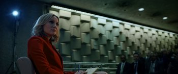 Movie still from “The Report” (2019), directed by Scott Z. Burns – A woman in a red jacket is writing on a piece of paper; Medium shot, Low angle