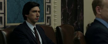 Movie still from “The Report” (2019), directed by Scott Z. Burns – A man in a suit sitting in a chair; Close Up shot, Over the shoulder angle