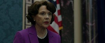 Movie still from “The Report” (2019), directed by Scott Z. Burns – A person wearing a suit and a pearl necklace; Close Up shot, Over the shoulder angle