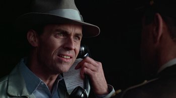 Movie still from “The Right Stuff” (1983), directed by Philip Kaufman – A man wearing a hat talking on a phone; Close Up shot, Low angle