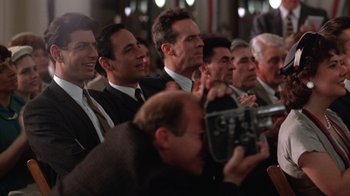 Movie still from “The Right Stuff” (1983), directed by Philip Kaufman – A group of men in suits and ties sitting next to each other; Medium shot, Over the shoulder angle