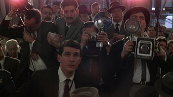 Movie still from “The Right Stuff” (1983), directed by Philip Kaufman – A group of men in suits and hats taking pictures of themselves; Medium shot, Low angle