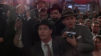 Movie still from “The Right Stuff” (1983), directed by Philip Kaufman – A group of men in suits and fedora hats holding cameras; Medium shot, Over the shoulder angle