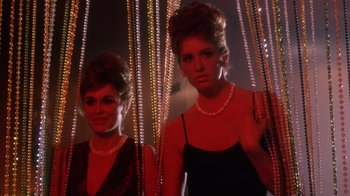 Movie still from “The Right Stuff” (1983), directed by Philip Kaufman – Two young women standing next to each other wearing necklaces; Medium shot, Low angle