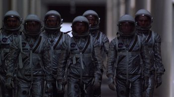 Movie still from “The Right Stuff” (1983), directed by Philip Kaufman – A group of men in space suits are standing in a line; Wide shot, Low angle