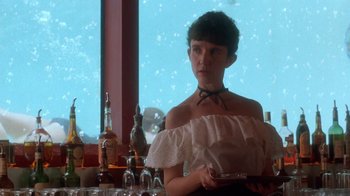 A woman in a white top holding a plate in front of a window