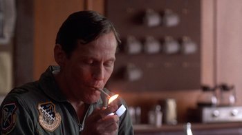 Movie still from “The Right Stuff” (1983), directed by Philip Kaufman – A man lighting a cigarette with a lighter in his mouth; Close Up shot, Low angle