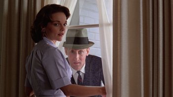 Movie still from “The Right Stuff” (1983), directed by Philip Kaufman – A man and a woman looking out of a window; Medium shot, Low angle
