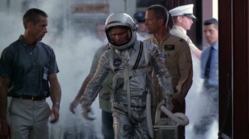 Movie still from “The Right Stuff” (1983), directed by Philip Kaufman – A man in a spacesuit is walking through smoke; Medium shot, Over the shoulder angle
