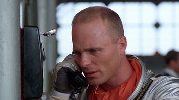 Movie still from “The Right Stuff” (1983), directed by Philip Kaufman – A man in a space suit talking on a cell phone; Close Up shot, Low angle