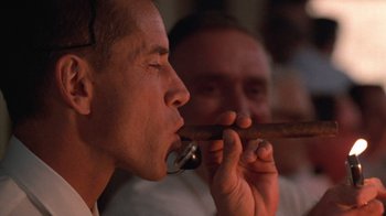 Movie still from “The Right Stuff” (1983), directed by Philip Kaufman – A man holding a cigar in his mouth while another man looks on; Close Up shot, Low angle