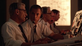 Movie still from “The Right Stuff” (1983), directed by Philip Kaufman – A group of men sitting at a table with microphones in front of them; Medium shot, Low angle
