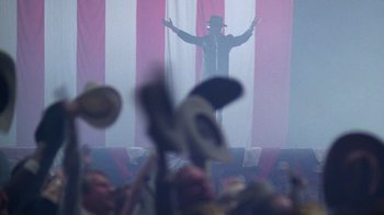 Movie still from “The Right Stuff” (1983), directed by Philip Kaufman – A man in a top hat is on a stage; Wide shot, Low angle
