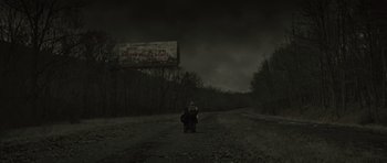Movie still from “The Road” (2009), directed by John Hillcoat – A person walking down a dirt road under a cloudy sky; Extreme Wide shot, Low angle