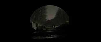 Movie still from “The Road” (2009), directed by John Hillcoat – Two people are standing under a bridge at night; Extreme Wide shot, Low angle