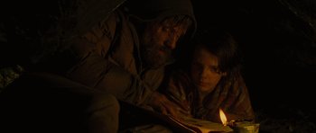 Movie still from “The Road” (2009), directed by John Hillcoat – A man and a boy are looking at a book; Medium shot, High angle