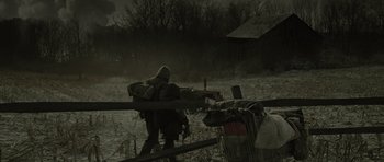 Movie still from “The Road” (2009), directed by John Hillcoat – A person with a backpack walking across a field; Wide shot, Over the shoulder angle