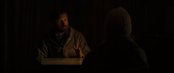 Movie still from “The Road” (2009), directed by John Hillcoat – A man sitting at a table in a dark room; Medium shot, Over the shoulder angle