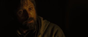 Movie still from “The Road” (2009), directed by John Hillcoat – A man with long hair and a goatee stares into the camera; Close Up shot, Over the shoulder angle