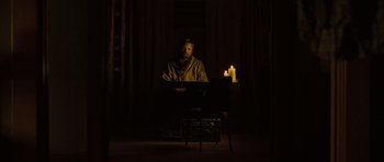 Movie still from “The Road” (2009), directed by John Hillcoat – A man sitting in front of a computer in a dimly - lit room; Wide shot, Over the shoulder angle