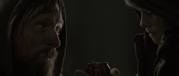 Movie still from “The Road” (2009), directed by John Hillcoat – A man with a beard holding a can in his hand; Close Up shot, Over the shoulder angle