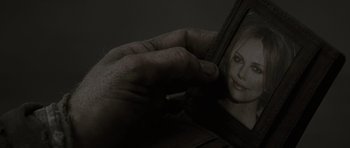Movie still from “The Road” (2009), directed by John Hillcoat – A hand holding a cigarette in front of a woman's reflection in a mirror; Extreme Close Up shot, Over the shoulder angle
