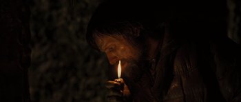 Movie still from “The Road” (2009), directed by John Hillcoat – A man lighting a candle in the dark; Close Up shot, High angle