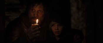 Movie still from “The Road” (2009), directed by John Hillcoat – A man and a boy holding a lit candle in the dark; Close Up shot, Over the shoulder angle