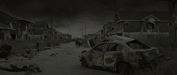 Movie still from “The Road” (2009), directed by John Hillcoat – Two people walking down a street next to an abandoned car; Extreme Wide shot, High angle