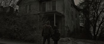 Movie still from “The Road” (2009), directed by John Hillcoat – Two people standing in front of an abandoned house; Wide shot, Low angle