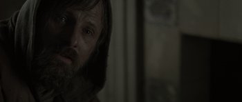 Movie still from “The Road” (2009), directed by John Hillcoat – A person with a beard looking at the camera; Close Up shot, Over the shoulder angle
