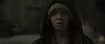Movie still from “The Road” (2009), directed by John Hillcoat – A young person wearing a hooded jacket and a fur hat; Close Up shot, Over the shoulder angle
