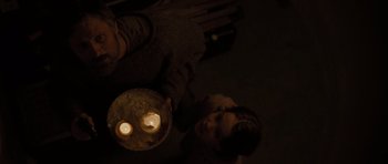 Movie still from “The Road” (2009), directed by John Hillcoat – A man holding a plate with candles in it; Medium shot, High angle