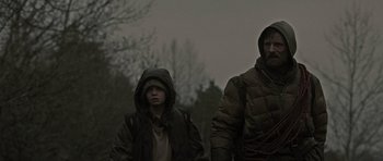 Movie still from “The Road” (2009), directed by John Hillcoat – A man and a boy are walking in the rain; Medium shot, Low angle