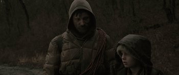 Movie still from “The Road” (2009), directed by John Hillcoat – A man and a child in a dark forest; Medium shot, Over the shoulder angle