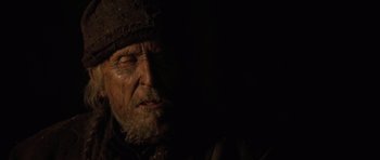 Movie still from “The Road” (2009), directed by John Hillcoat – An old man wearing a hat is looking at the camera; Close Up shot, Low angle