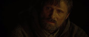 Movie still from “The Road” (2009), directed by John Hillcoat – A person with a beard looking at the camera; Close Up shot, Over the shoulder angle