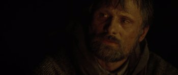 Movie still from “The Road” (2009), directed by John Hillcoat – A person with a beard looking at the camera; Close Up shot, Over the shoulder angle