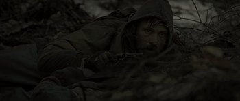 Movie still from “The Road” (2009), directed by John Hillcoat – A man with a rifle in a dark forest; Medium shot, Over the shoulder angle