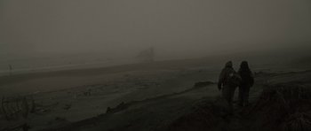 Movie still from “The Road” (2009), directed by John Hillcoat – A person standing on a beach in the fog; Extreme Wide shot, Low angle