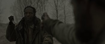 Movie still from “The Road” (2009), directed by John Hillcoat – Two men in the woods one of whom is pointing at the camera; Close Up shot, Over the shoulder angle