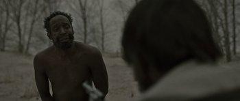 Movie still from “The Road” (2009), directed by John Hillcoat – A man standing next to another man on a beach; Close Up shot, Over the shoulder angle